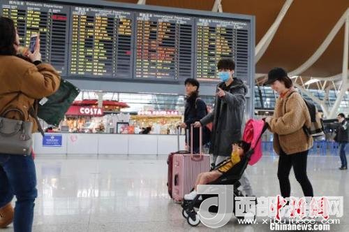 旅客帶著孩子前往辦票柜臺辦理登機(jī)手續(xù)。　殷立勤 攝