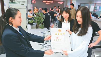 河北省承德市網(wǎng)絡(luò)代購經(jīng)營者陳晨(右)從工作人員手中接過帶有統(tǒng)一社會信用代碼的營業(yè)執(zhí)照。 劉環(huán)宇攝(人民圖片)